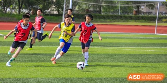 Two students from Rugao International Academy BFSU playing soccer on a field.