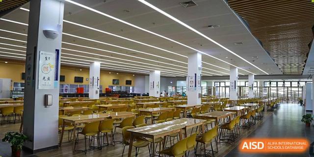 The cafeteria with wooden tables and chairs at Rugao International Academy BFSU.