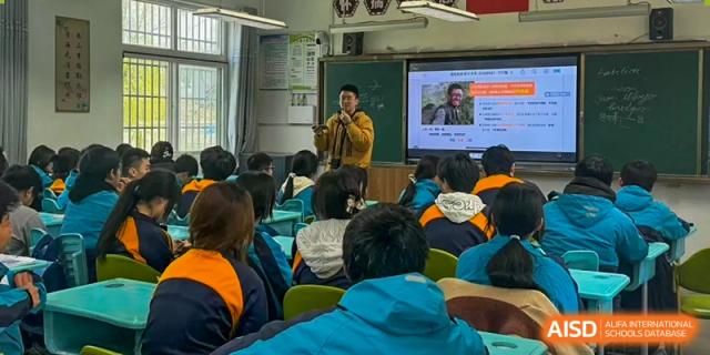 A teacher giving a presentation to a class of students in a classroom with a large screen displaying information at Shanghai Wenlai International School.