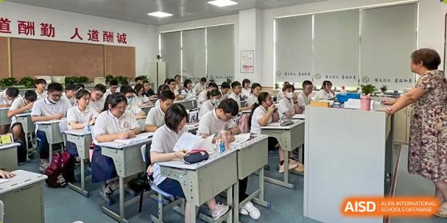 A wide view of a modern classroom with many students seated at desks, writing or studying at Shanghai Wenlai International School.
