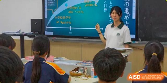 A female teacher pointing to text on a large digital screen while teaching a lesson to students in a classroom at Shanghai Wenlai International School.