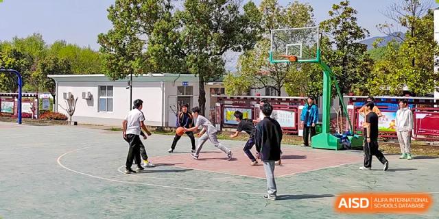 A group of male students playing basketball on an outdoor court at Shanghai Wenlai International School.