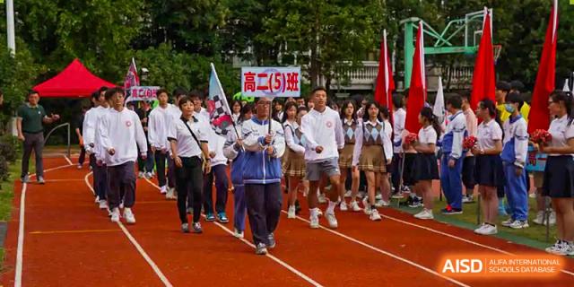 A large group of students in uniform marching on a red track during a school event or parade at Shanghai Wenlai International School.