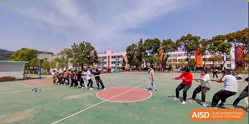 A wide view of students playing a sport, possibly handball or dodgeball, on a circular court area during a sports day at Shanghai Wenlai International School.