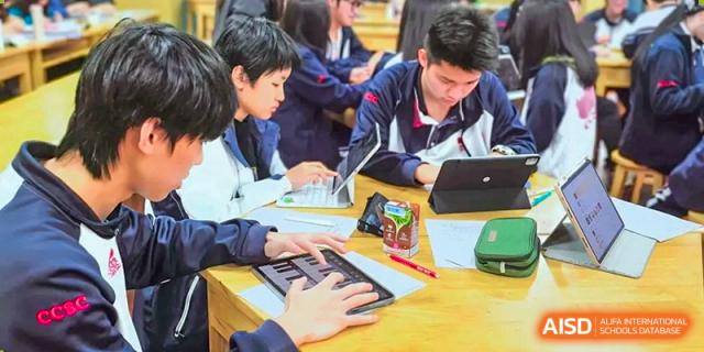 Two students at Shenzhen (Nanshan) Concord College of Sino-Canada focused on a project with a tablet and a small piano keyboard.
