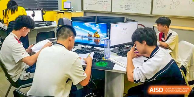 A group of male students at Shenzhen (Nanshan) Concord College of Sino-Canada collaborating at a computer station.