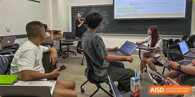 A teacher at Shenzhen (Nanshan) Concord College of Sino-Canada instructing a student in a classroom at a computer.