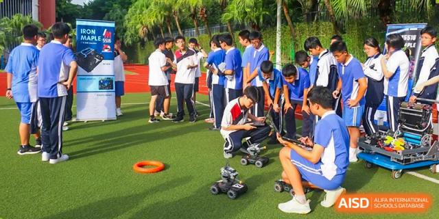 A group of students at Shenzhen (Nanshan) Concord College of Sino-Canada controlling robots with remotes on a grassy field.