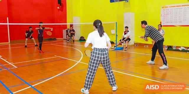 A student at Shenzhen (Nanshan) Concord College of Sino-Canada playing badminton in a gym.