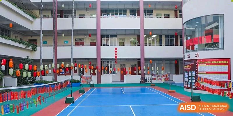 An empty outdoor badminton court next to a school building at Shenzhen (Nanshan) Concord College of Sino-Canada.