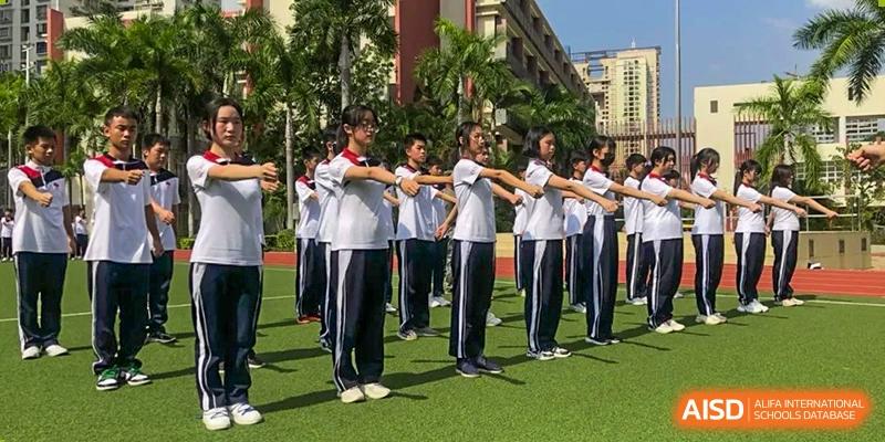 Students at Shenzhen (Nanshan) Concord College of Sino-Canada participating in a group exercise on a green sports field.
