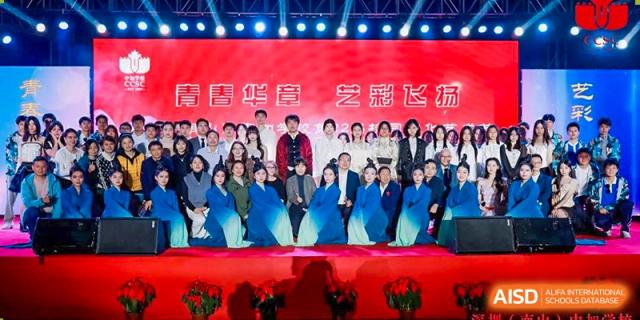 A group photo of teachers and staff at Shenzhen (Nanshan) Concord College of Sino-Canada posing on a red stage.