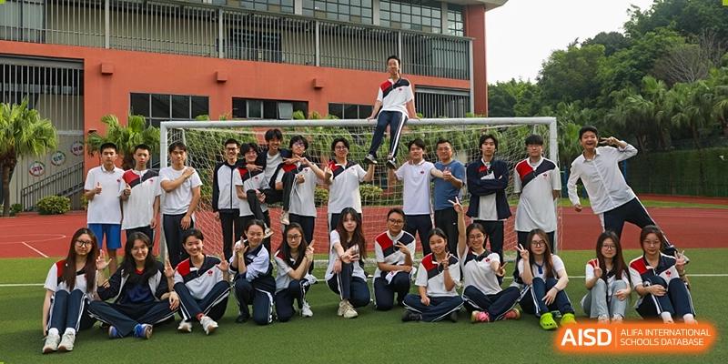 A large group of students and a teacher at Shenzhen (Nanshan) Concord College of Sino-Canada posing for a fun group photo outside a school building.