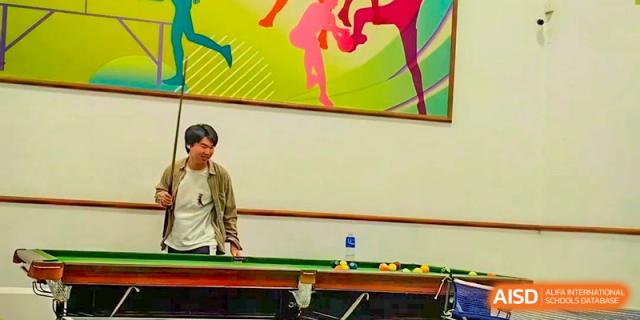 A student at Shenzhen (Nanshan) Concord College of Sino-Canada playing billiards in a recreation room.