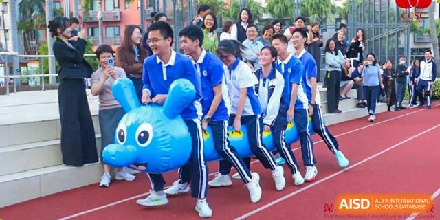 Students at Shenzhen (Nanshan) Concord College of Sino-Canada running with a large blue inflatable bird during a fun event.