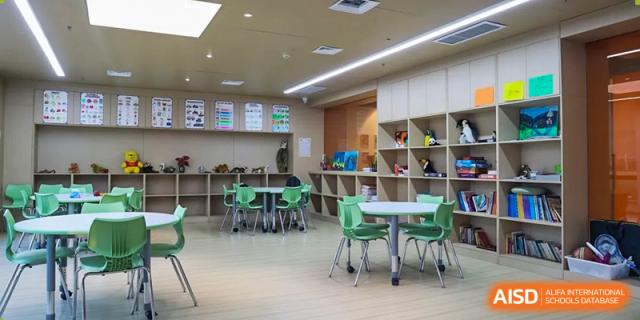 A well-lit, open student learning area at Sias International School with tables, green chairs, and light wood cabinetry.