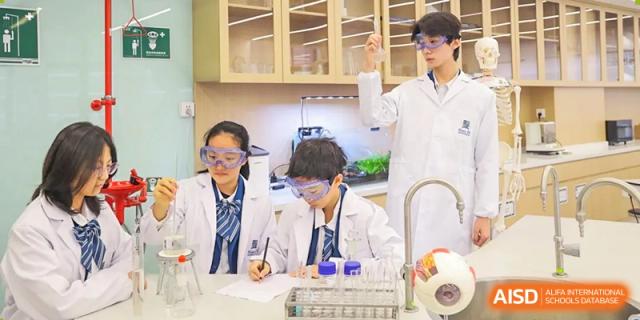 Students at Sias International School conduct an experiment in a science laboratory, wearing safety goggles and lab coats.