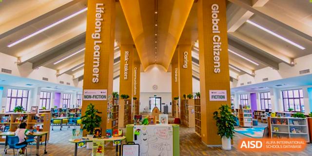 Interior view of the spacious, brightly lit library at Sias International School with high, wood-paneled ceilings and colorful displays.