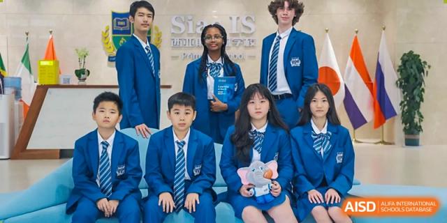 Two young students from Sias International School wearing navy blue uniforms are seated with a group of older students.