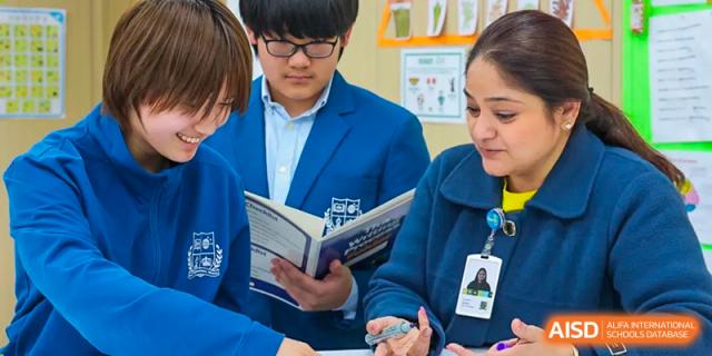 Close-up of a student in a blue jacket reading an open book at Sias International School.