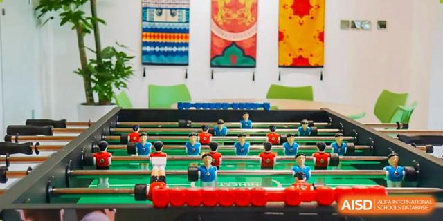 Close-up shot of a foosball table with players and bright wall art hanging above it in a student common area at Sias International School.