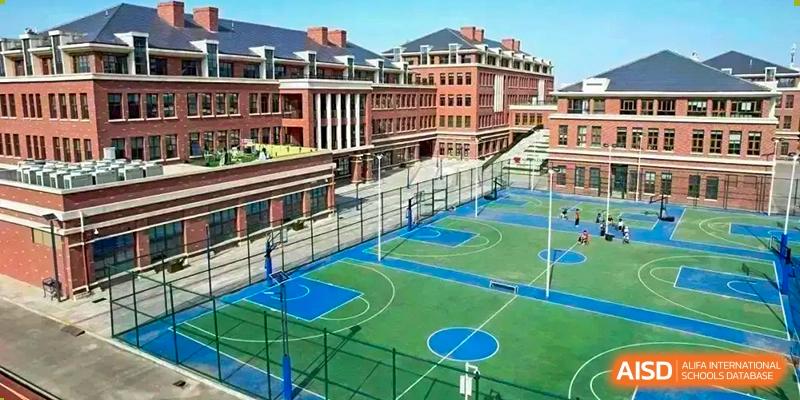 Outdoor view of the sports complex at Sias International School with a blue-and-green basketball court surrounded by classic red-brick school buildings.