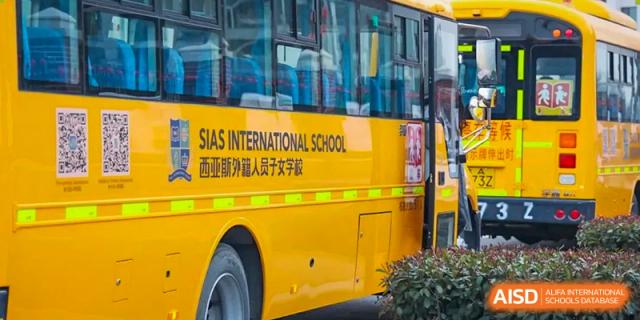 Close-up of a bright yellow Sias International School bus with the school name and logo clearly visible on the side.