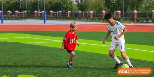 Young student in a red shirt running on the bright green sports field at Sias International School during an outdoor activity.