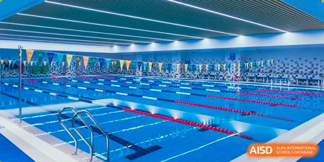 Indoor view of the bright, blue swimming pool and lanes at Sias International School, ready for aquatic sports and lessons.