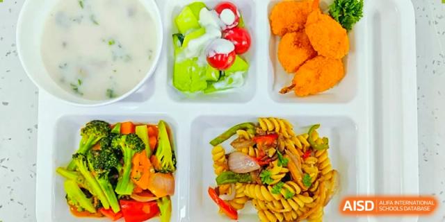 A colorful lunch tray at Sias International School with a portion of pasta salad, a side salad, and a piece of chicken.