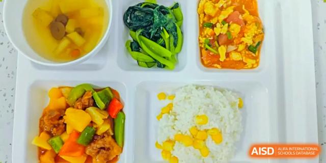 A lunch tray at Sias International School showing a healthy meal of green vegetables, yellow rice, and a piece of chicken.