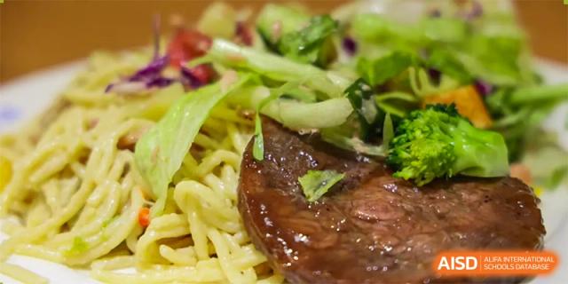 A meal tray at Sias International School with noodles, sliced beef, and a green salad.