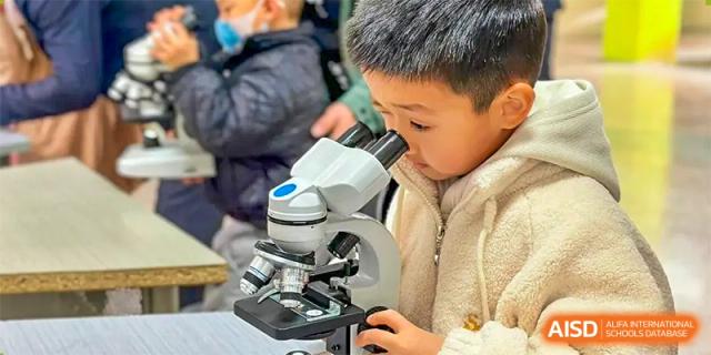 A young boy is looking through a microscope in a science class at SUZHOU INTERNATIONAL FOREIGN LANGUAGE SCHOOL.