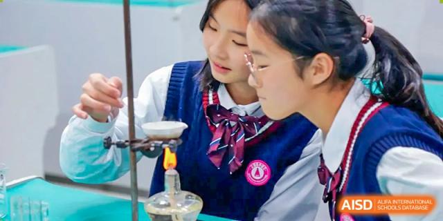 Two female students are performing a science experiment with a Bunsen burner at SUZHOU INTERNATIONAL FOREIGN LANGUAGE SCHOOL.