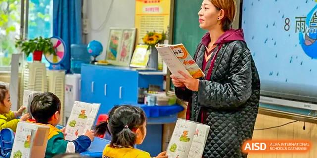 A female teacher is reading a book to a group of young students in a classroom at SUZHOU INTERNATIONAL FOREIGN LANGUAGE SCHOOL.