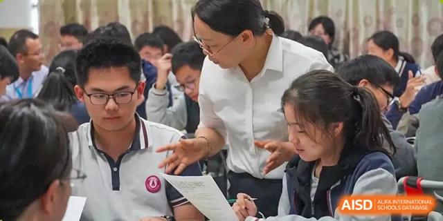 A female teacher is helping a group of students in a classroom at SUZHOU INTERNATIONAL FOREIGN LANGUAGE SCHOOL.
