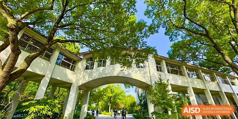 A walking path with lush trees and an archway leading to a building on the campus of SUZHOU INTERNATIONAL FOREIGN LANGUAGE SCHOOL.