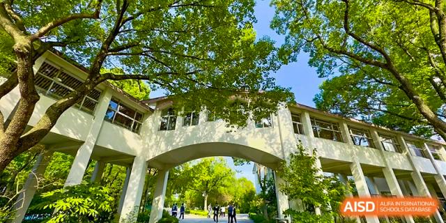 A walking path with lush trees and an archway leading to a building on the campus of SUZHOU INTERNATIONAL FOREIGN LANGUAGE SCHOOL.