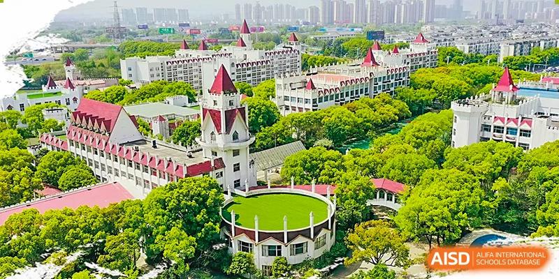 An aerial view of the SUZHOU INTERNATIONAL FOREIGN LANGUAGE SCHOOL, featuring a prominent white tower with a red conical roof and a circular green lawn in the foreground.