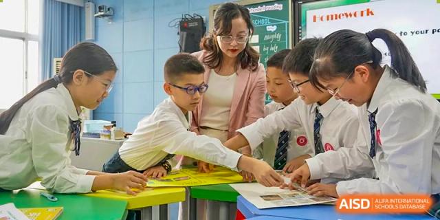 Students and a teacher collaborating on a project in a classroom at SUZHOU INTERNATIONAL FOREIGN LANGUAGE SCHOOL.