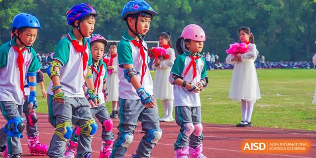Young students on rollerblades, wearing helmets and protective gear, holding flowers on a grassy field at SUZHOU INTERNATIONAL FOREIGN LANGUAGE SCHOOL.