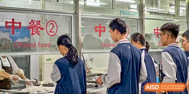 Students are serving themselves food from the cafeteria line at SUZHOU INTERNATIONAL FOREIGN LANGUAGE SCHOOL.