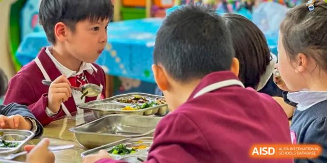 A young student is eating his meal from a metal lunch tray at SUZHOU INTERNATIONAL FOREIGN LANGUAGE SCHOOL.