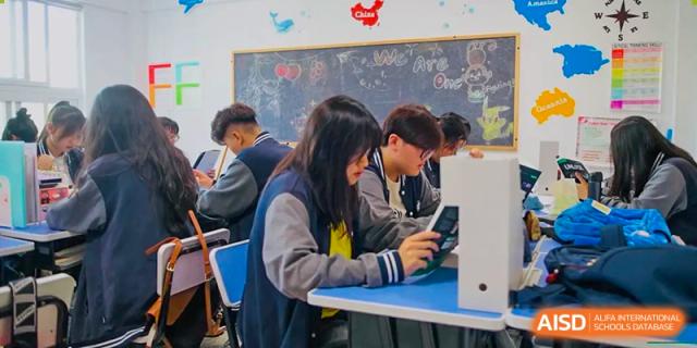 Students at The Experimental School Affiliated to Nanjing Normal University looking down at their phones at their desks.