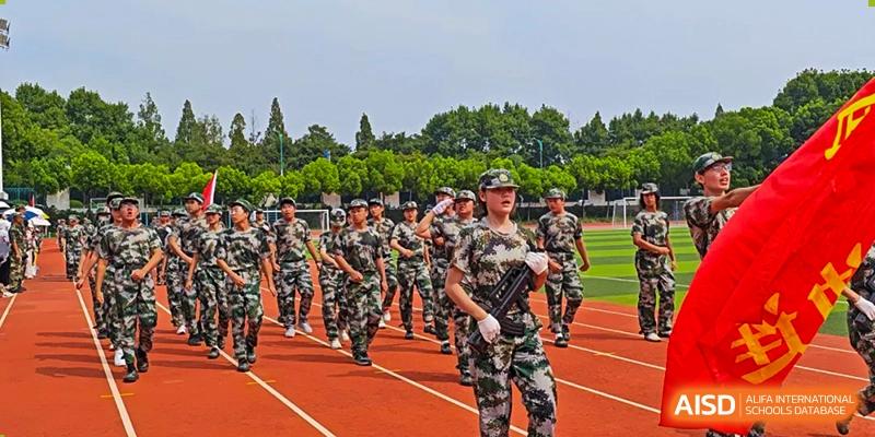 A line of students from The Experimental School Affiliated to Nanjing Normal University marching in camouflage uniforms on a track.