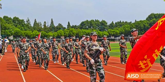 A line of students from The Experimental School Affiliated to Nanjing Normal University marching in camouflage uniforms on a track.
