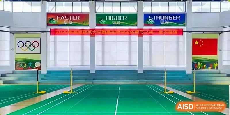 An empty indoor gymnasium or sports hall at The Experimental School Affiliated to Nanjing Normal University with banners hanging from the ceiling.