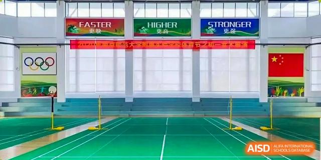 An empty indoor gymnasium or sports hall at The Experimental School Affiliated to Nanjing Normal University with banners hanging from the ceiling.