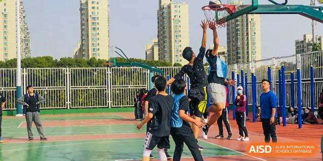 Students from The Experimental School Affiliated to Nanjing Normal University playing a game of basketball on an outdoor court.
