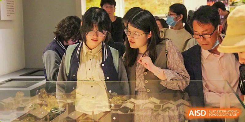 Two students from The Experimental School Affiliated to Nanjing Normal University are standing side-by-side, looking at something off-camera.